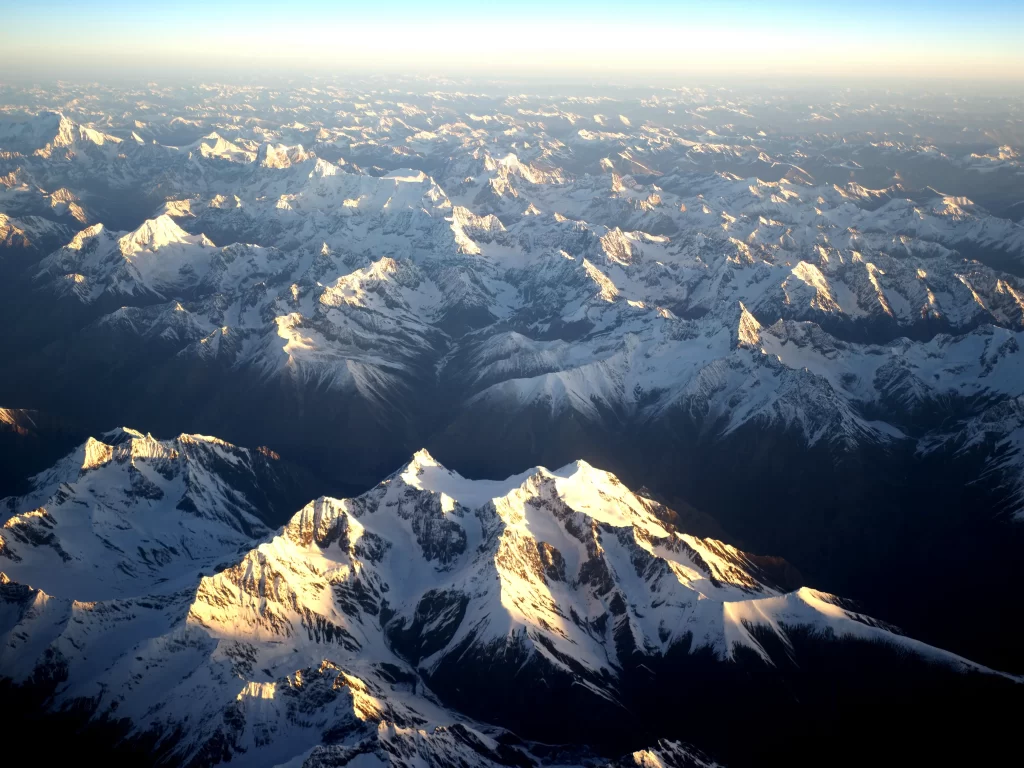 sunset golden snow-capped peaks mountain ridges shadowed valleys clear sky