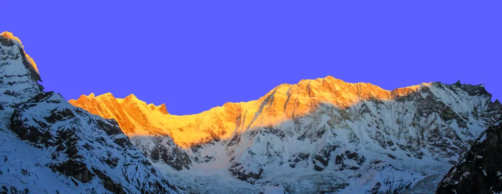 sunset snow-capped peaks golden clear blue sky rugged terrain sharp