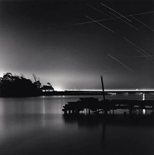 Nighttime Bridge Silhouetted Trees Reflective Water Star Trails